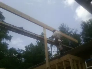 Carpenter setting a ridge beam over a new addition frame — Ice Dam Removal by Roofing Brothers in Gibsonton
