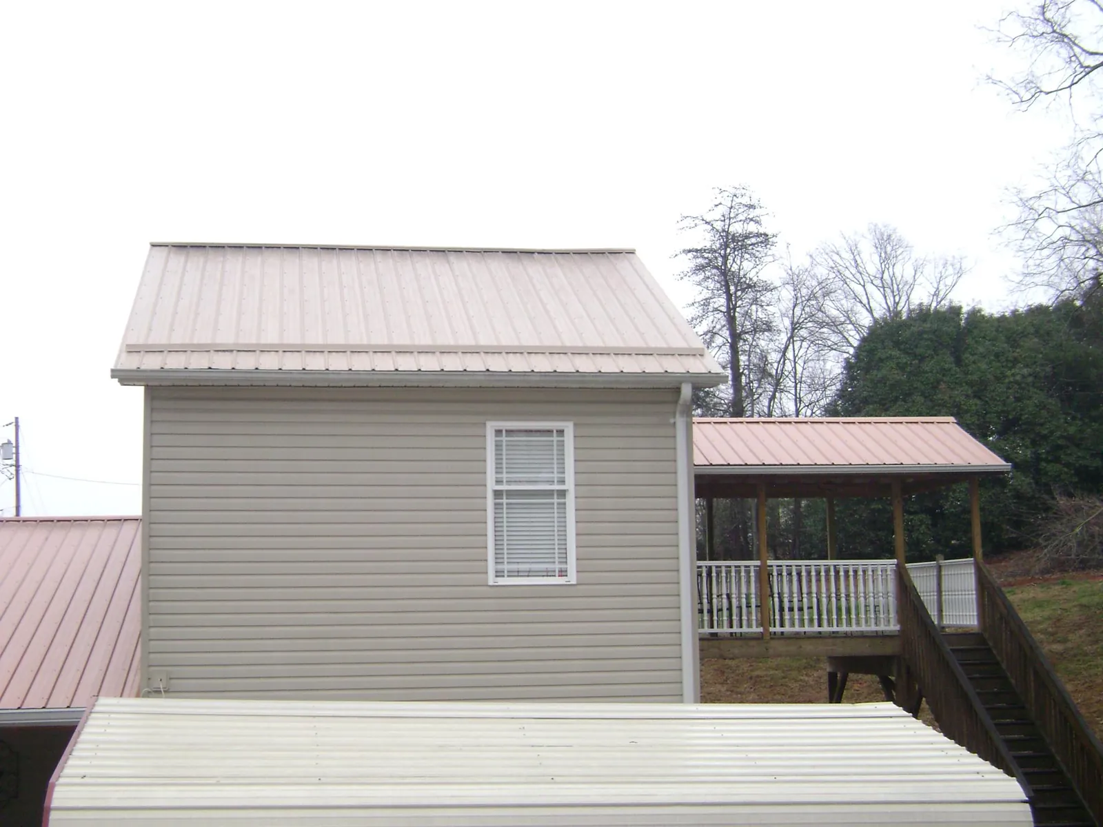 Tan metal roofs on a two story addition and attached porch, from a Roof Replacement job in Gibsonton