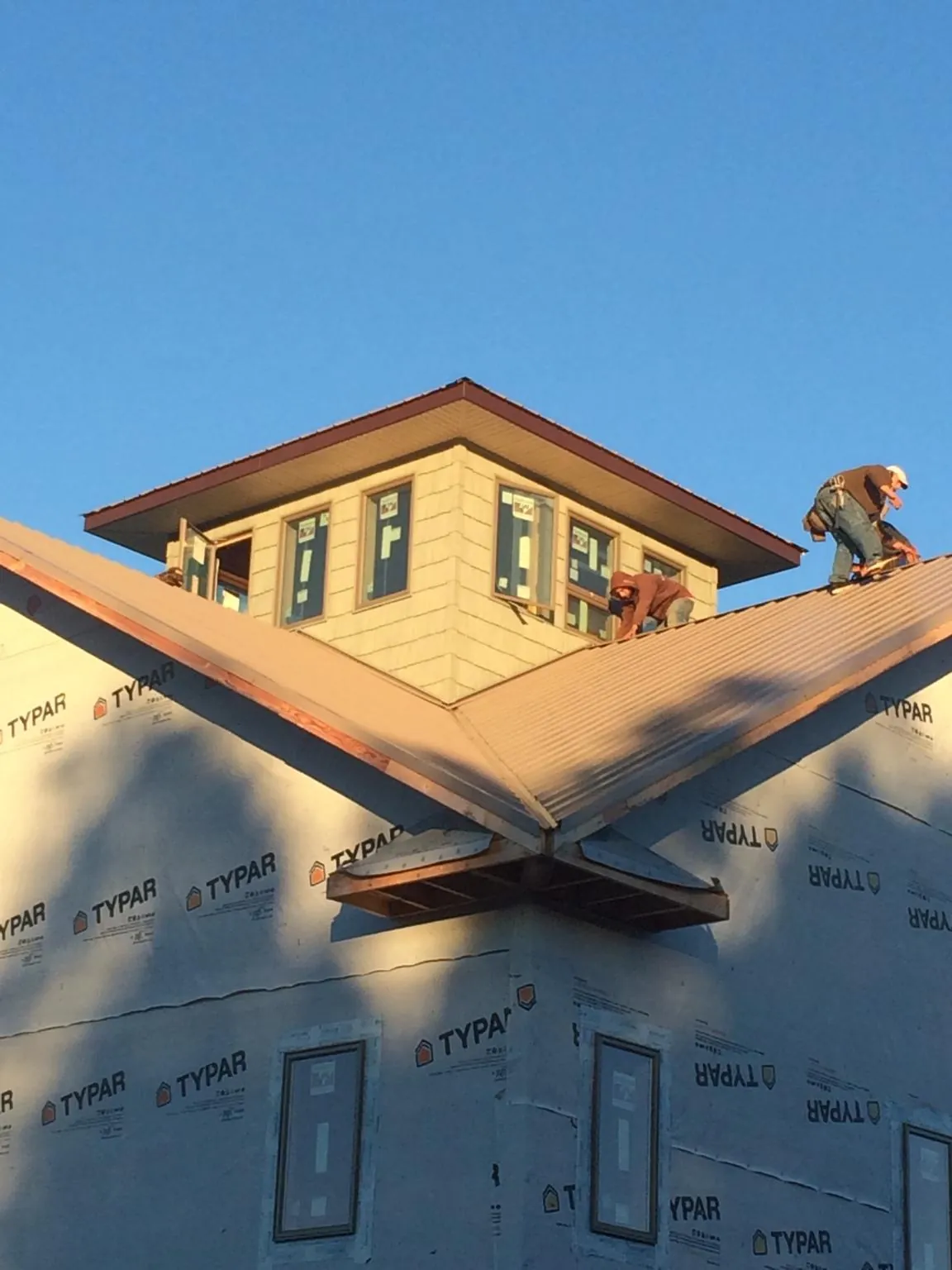 Roofers working around a rooftop cupola on a new metal roof at sunset — Roof Waterproofing in Gibsonton by Roofing Brothers